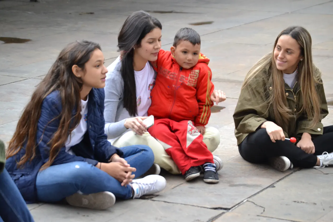 Adultos acompañando a niños sentados en el piso