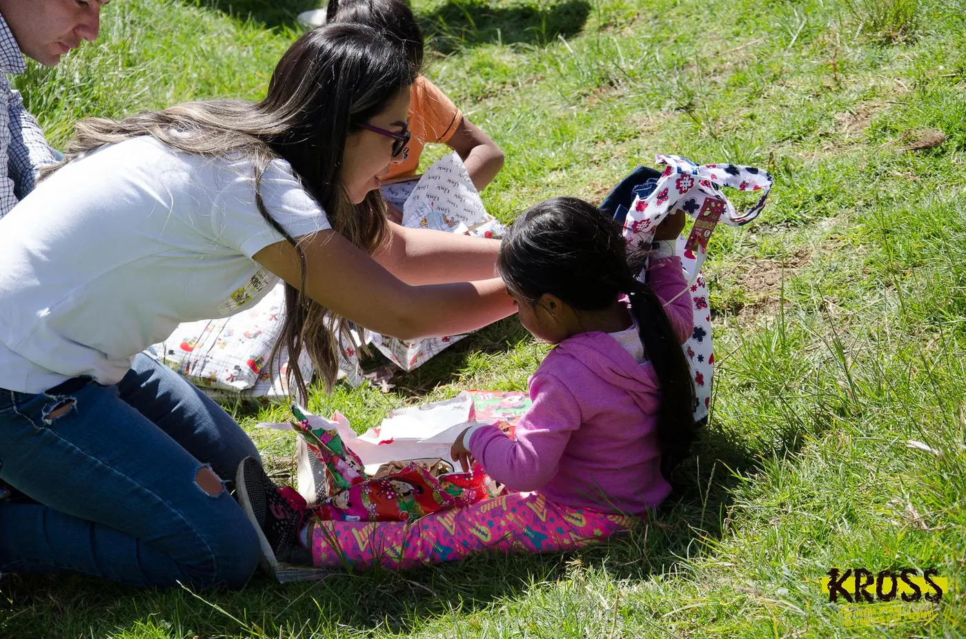 Una persona acompaña a una niña al abrir un regalo